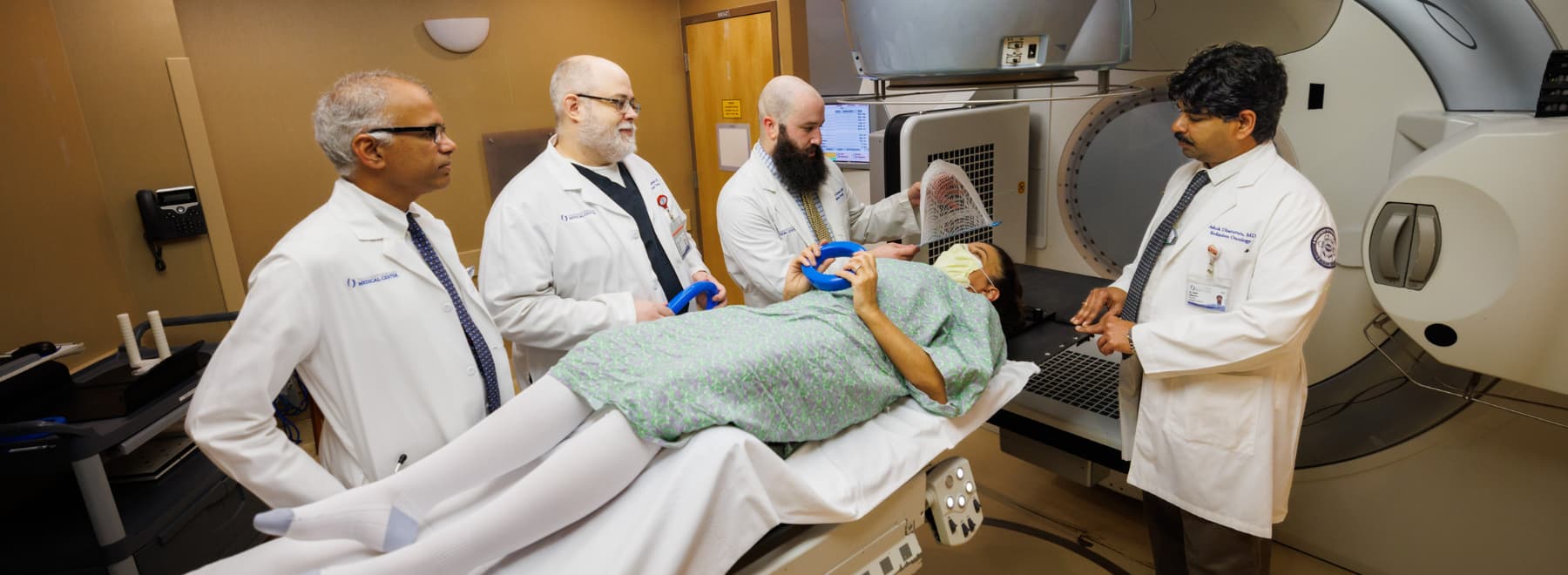 Four radiation oncologists work with a patient.